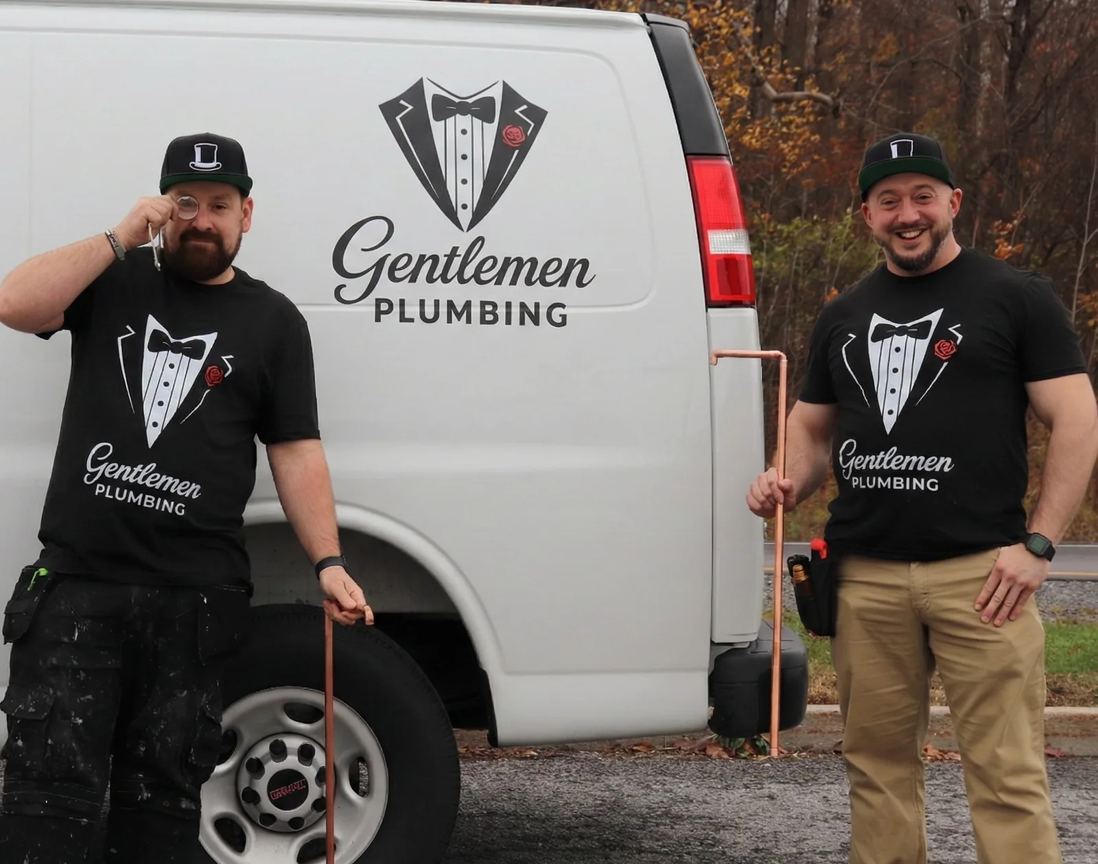 Gentlemen Plumbing team posing beside branded service van holding copper pipe