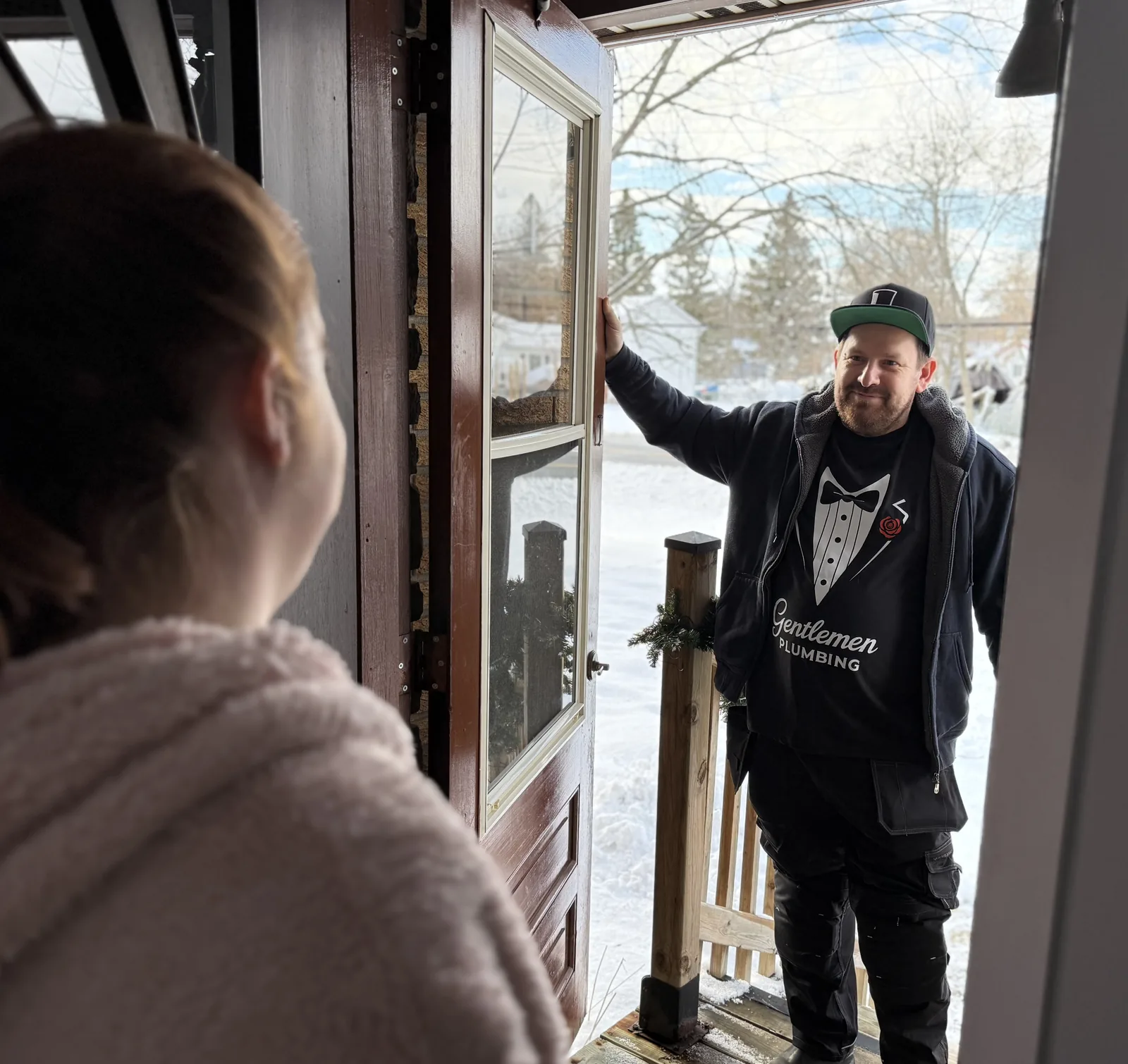 Plumber arriving at a front door while a homeowner opens it.