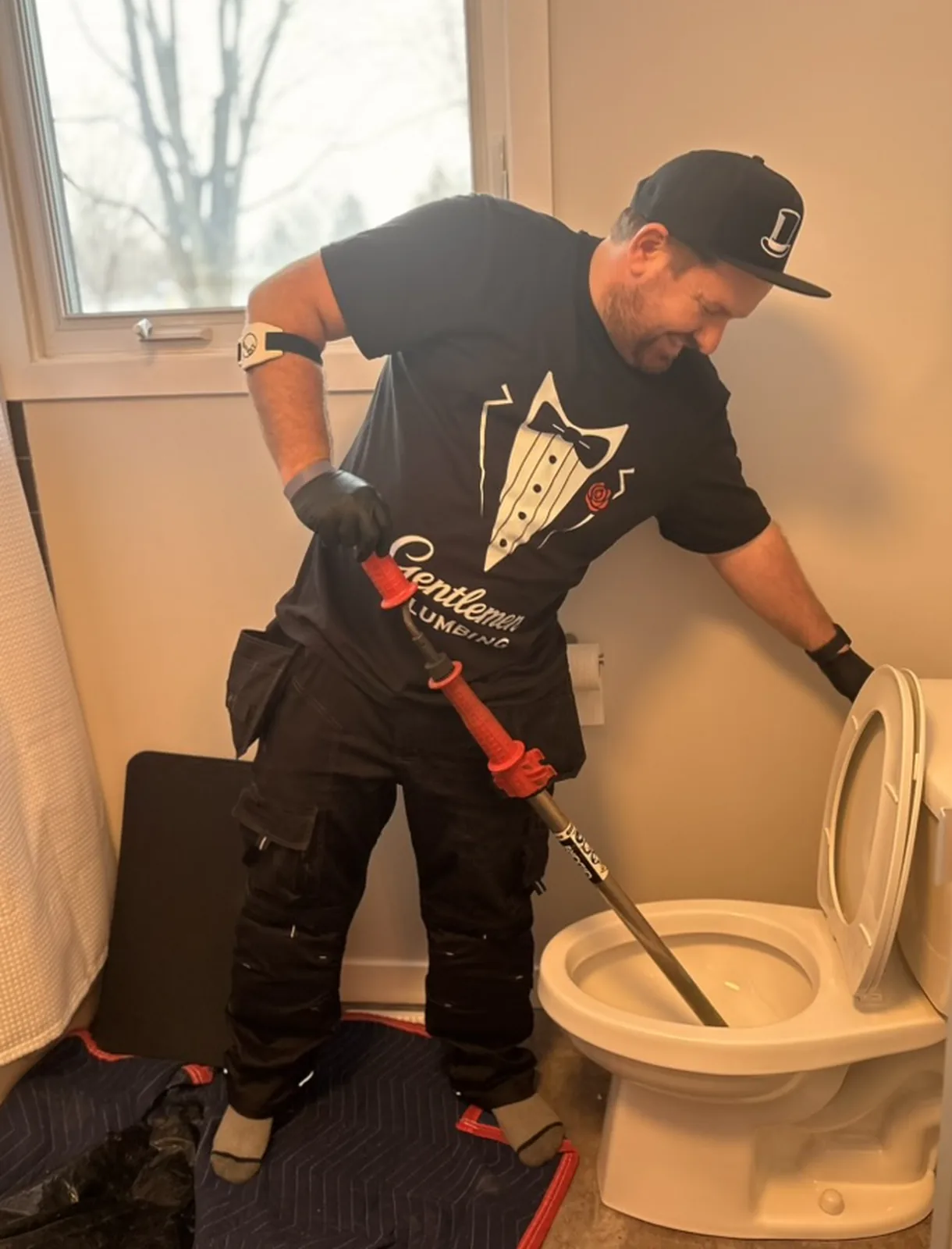 Gentlemen Plumbing plumber using a toilet auger to clear a clogged toilet.