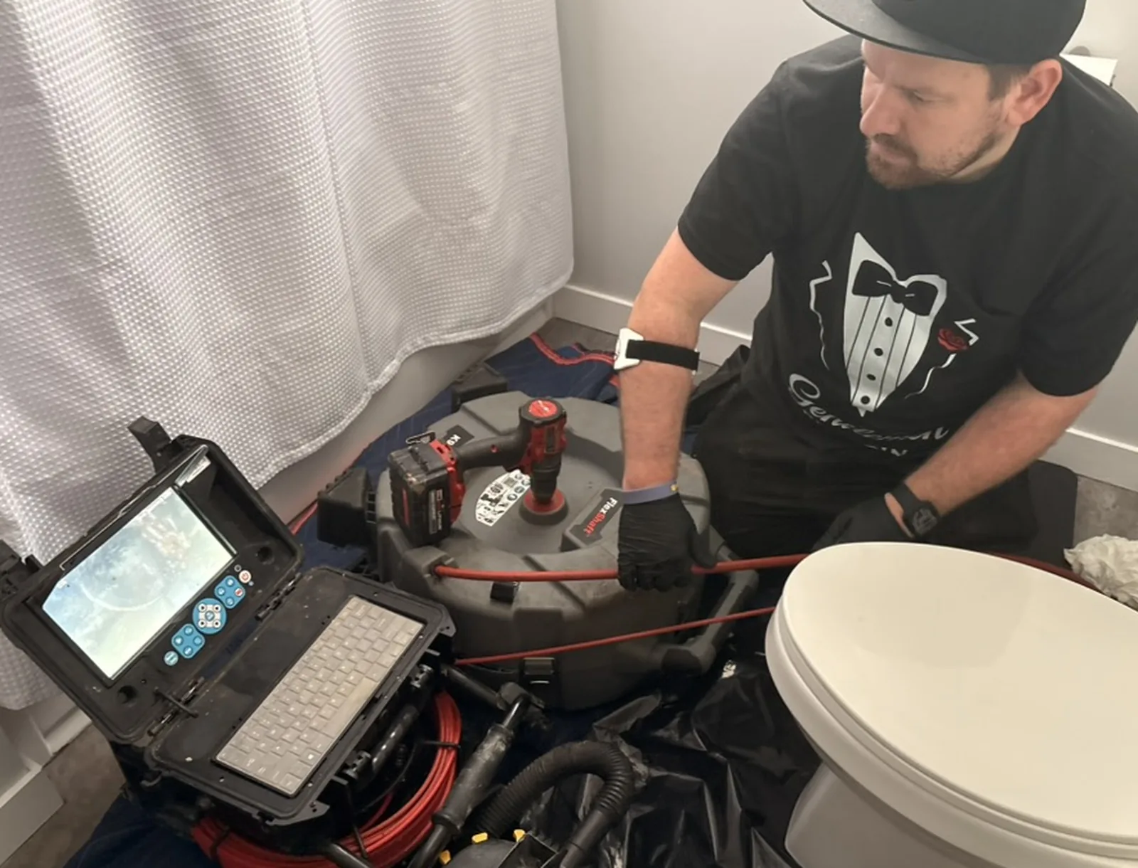 Technician guiding drain camera cable beside a toilet.