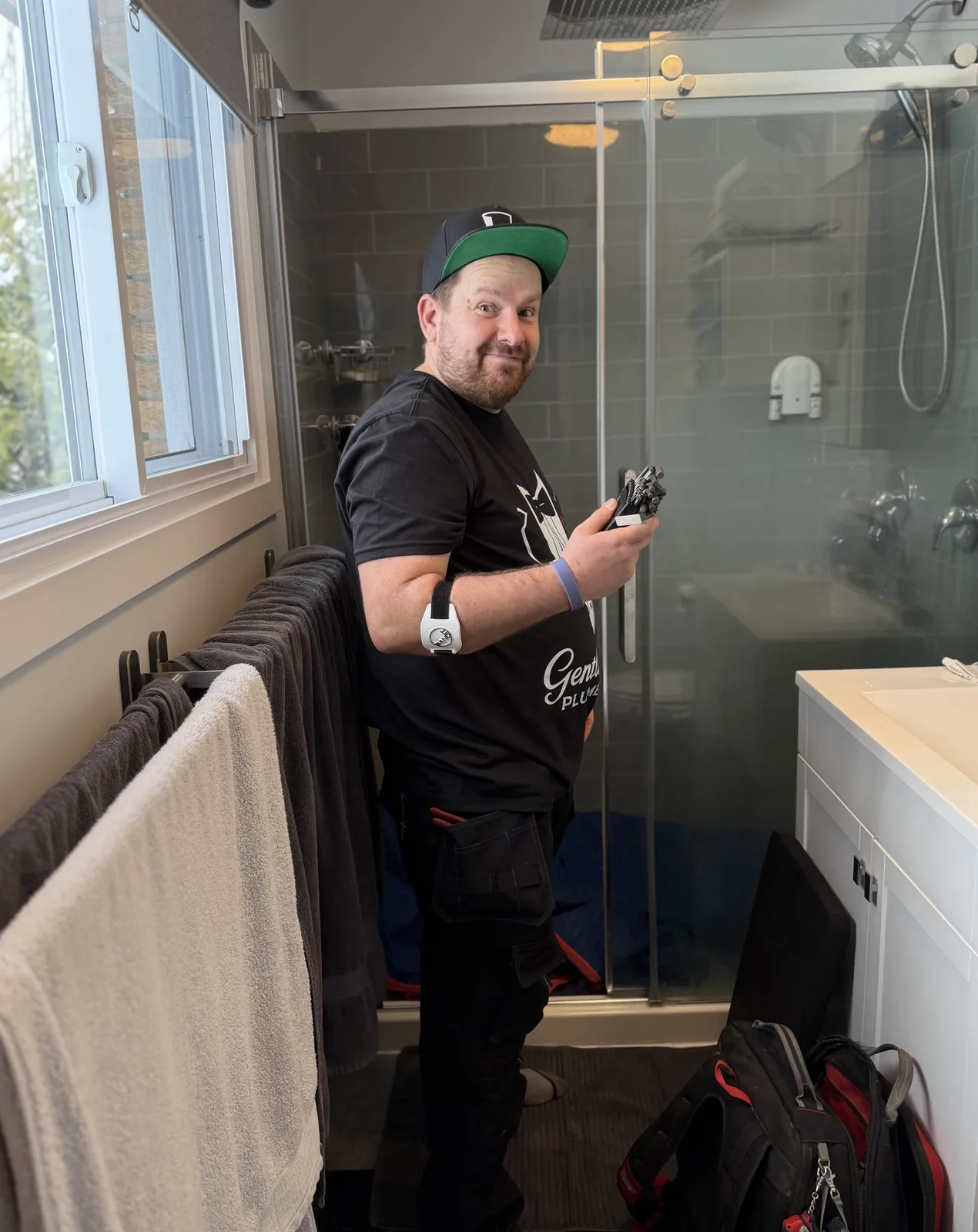 Gentlemen Plumbing plumber holding shower valve parts beside a shower.