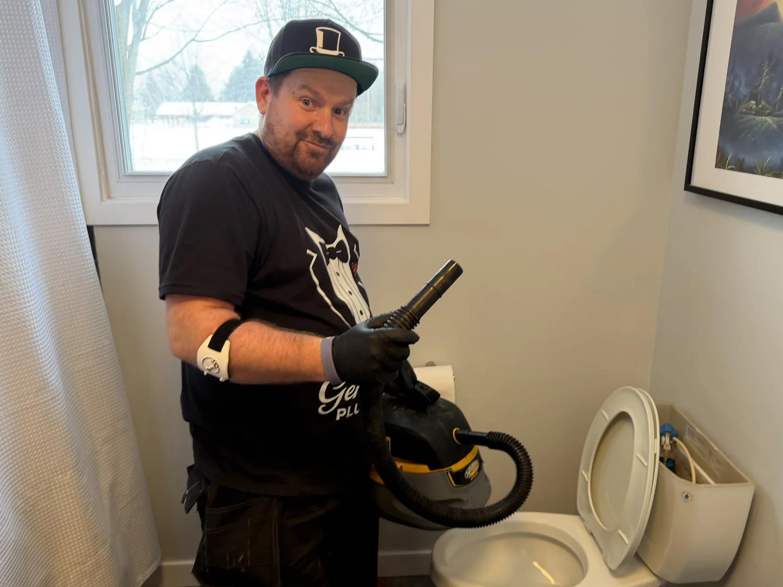 Plumber with wet vacuum beside a toilet