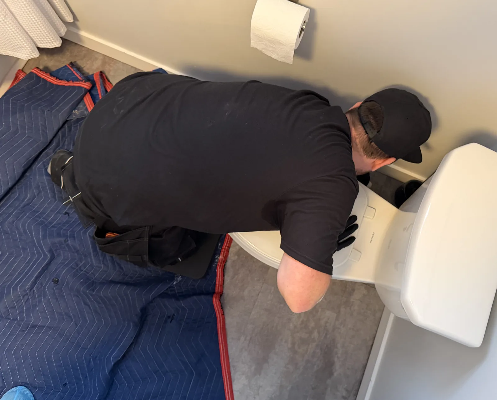 Plumber installing a toilet seat in a bathroom.