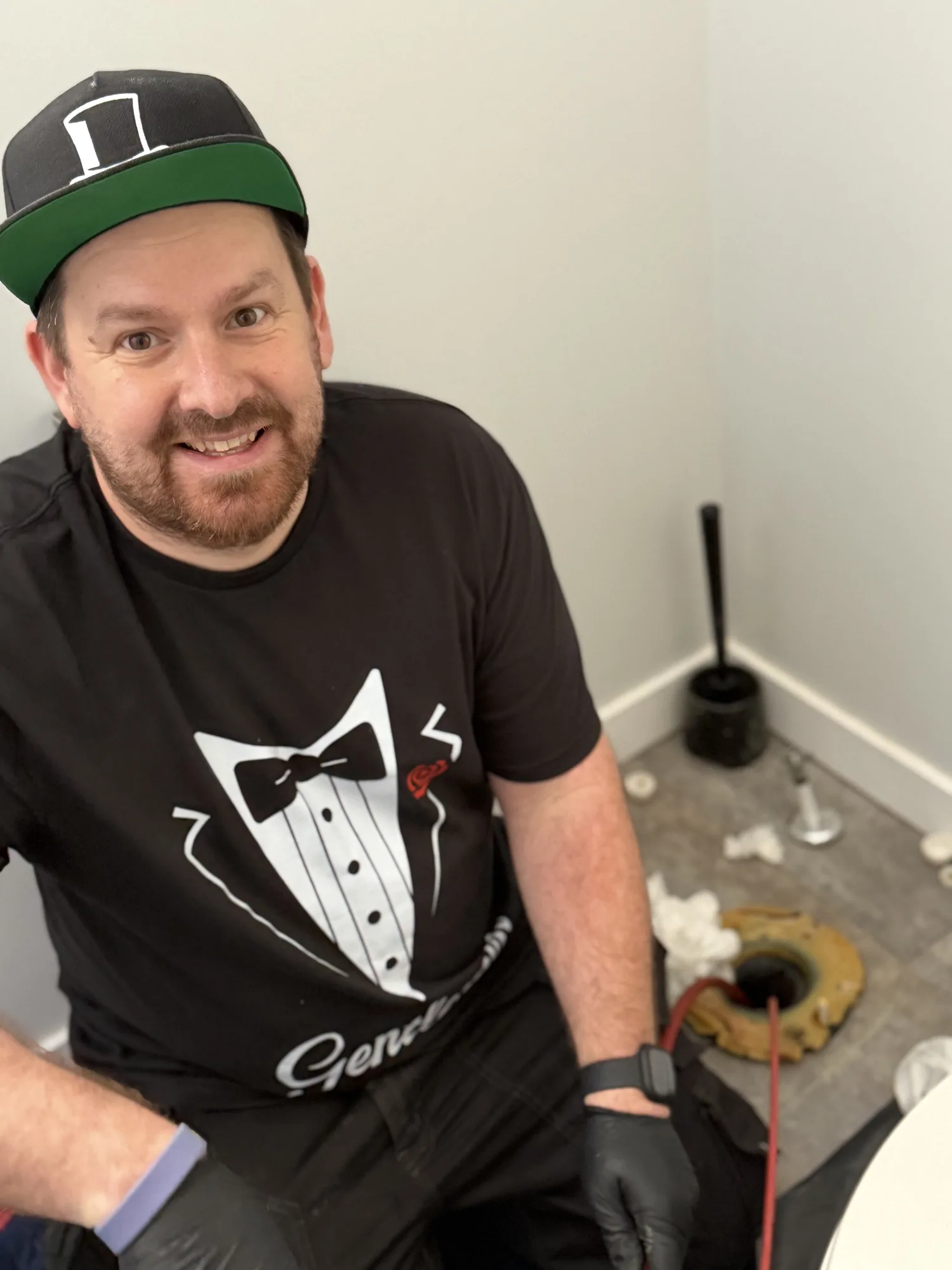 Jonathan kneeling beside an exposed toilet flange during a repair