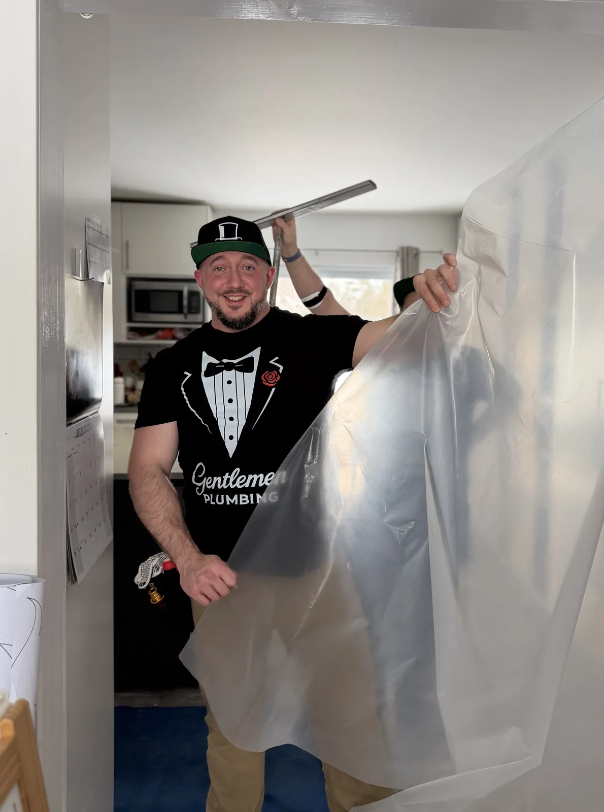 Jake lifting a plastic dust barrier sheet to section off the room and protect the home