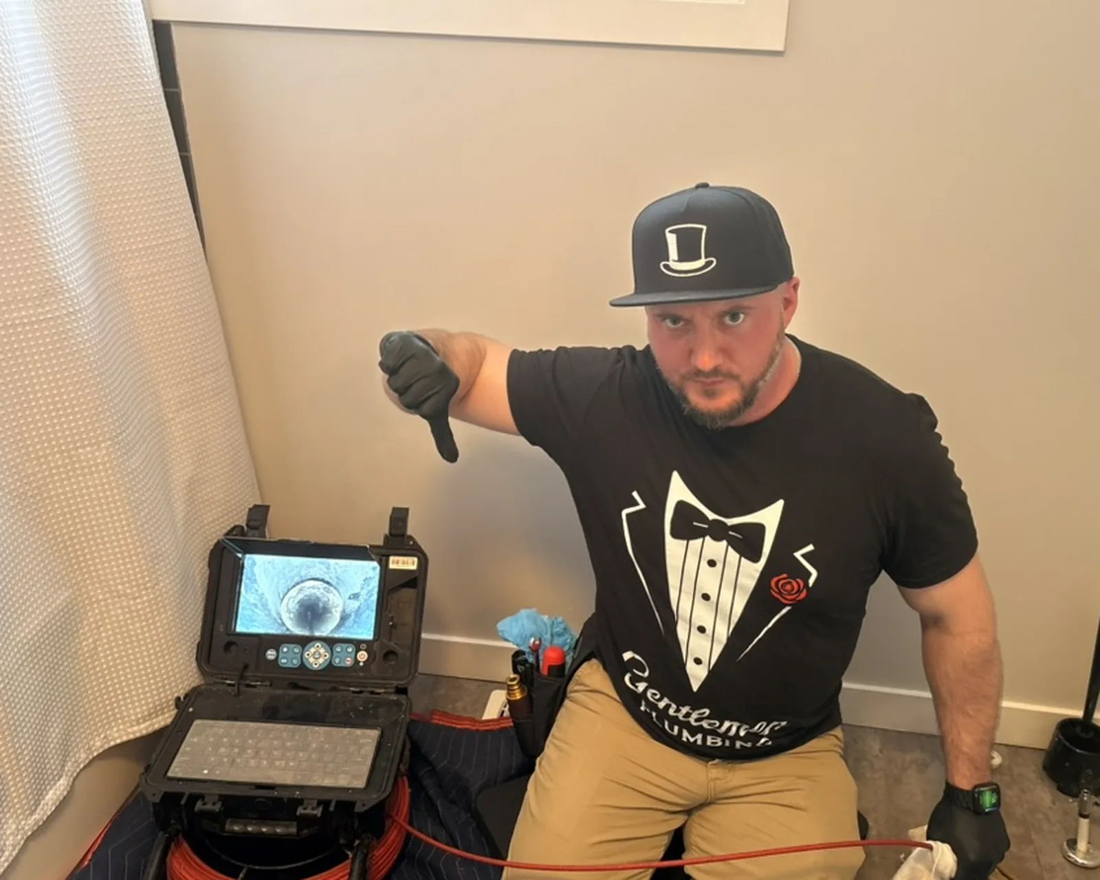Plumber pointing at a drain camera monitor while explaining sewer camera results.
