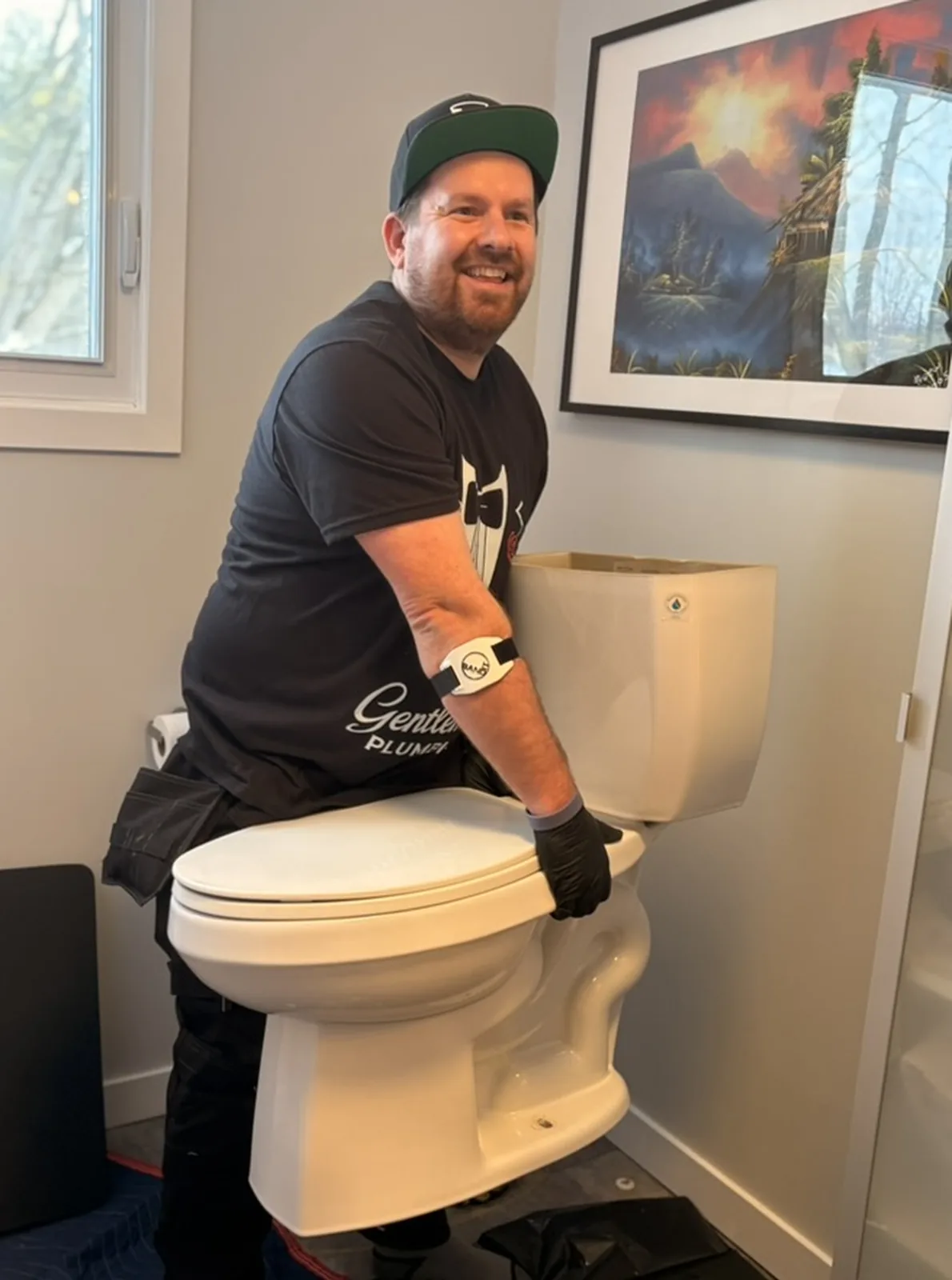 Plumber positioning a toilet during installation in a bathroom.