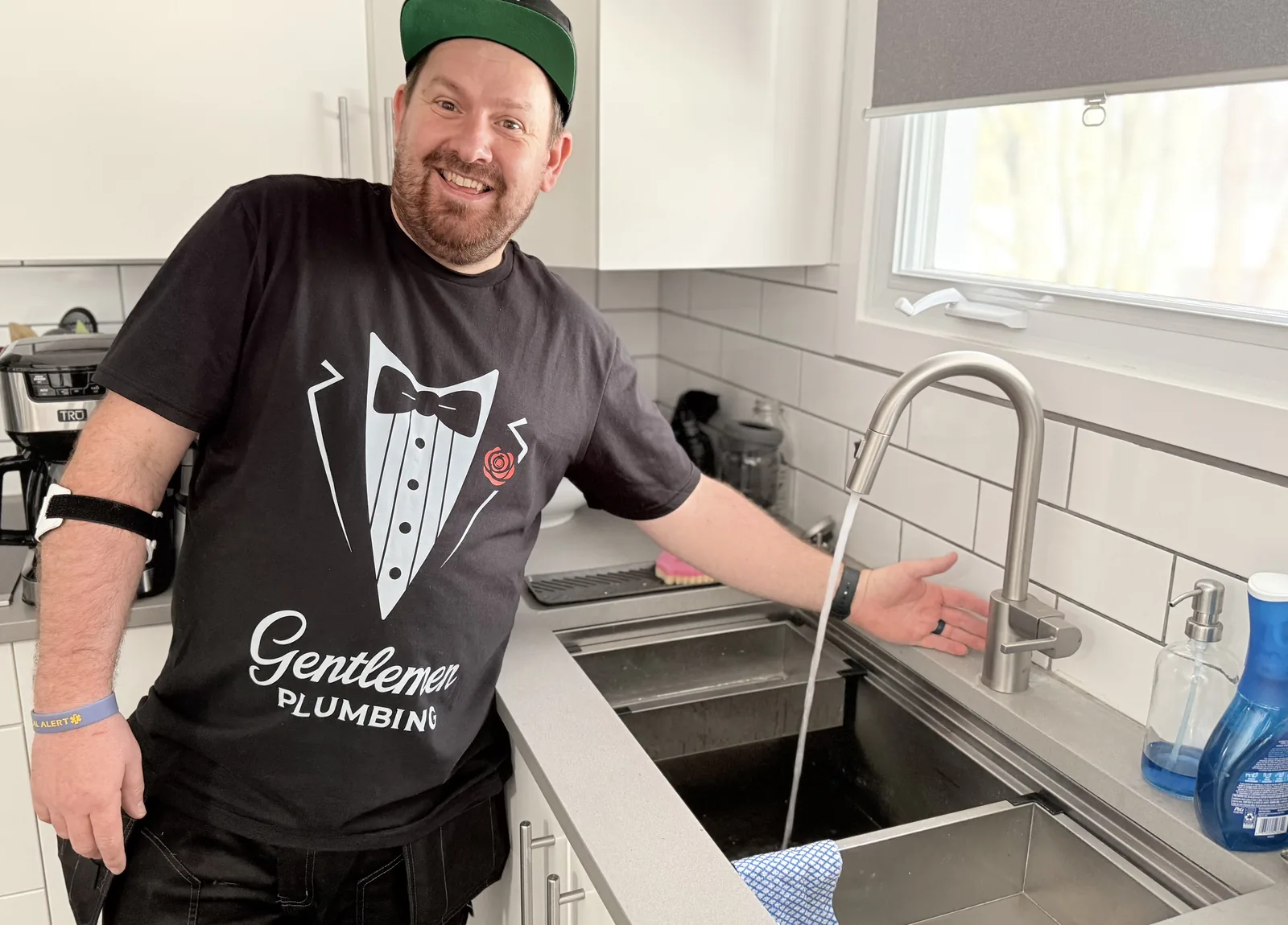 Plumber presenting a running kitchen faucet over a double sink.