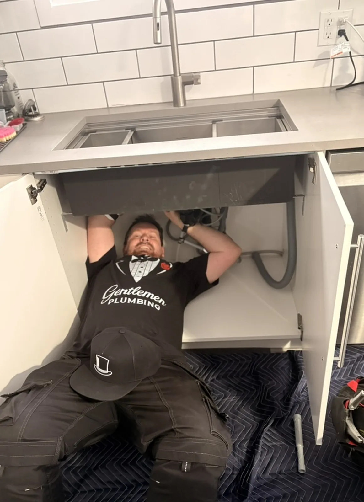 Gentlemen Plumbing plumber repairing plumbing under a kitchen sink.