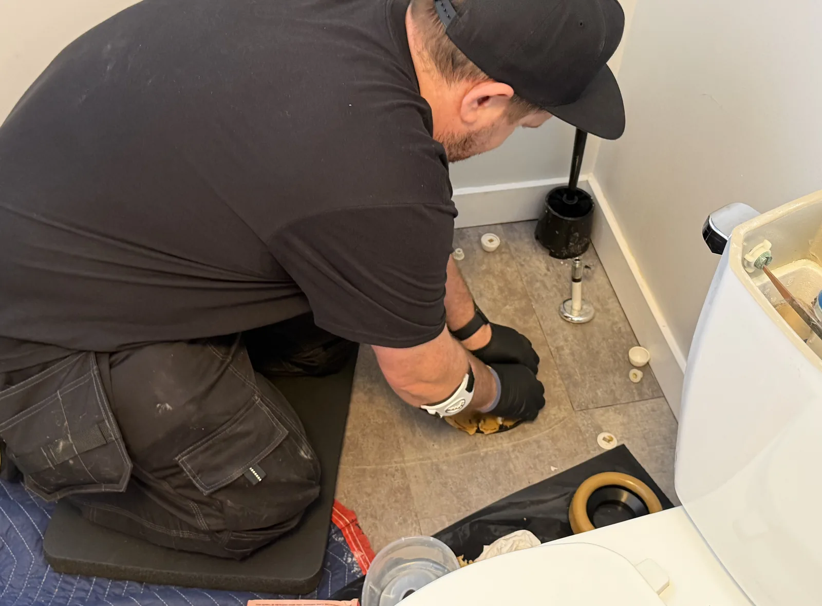 Gentlemen Plumbing technician repairing a toilet flange on a bathroom floor.