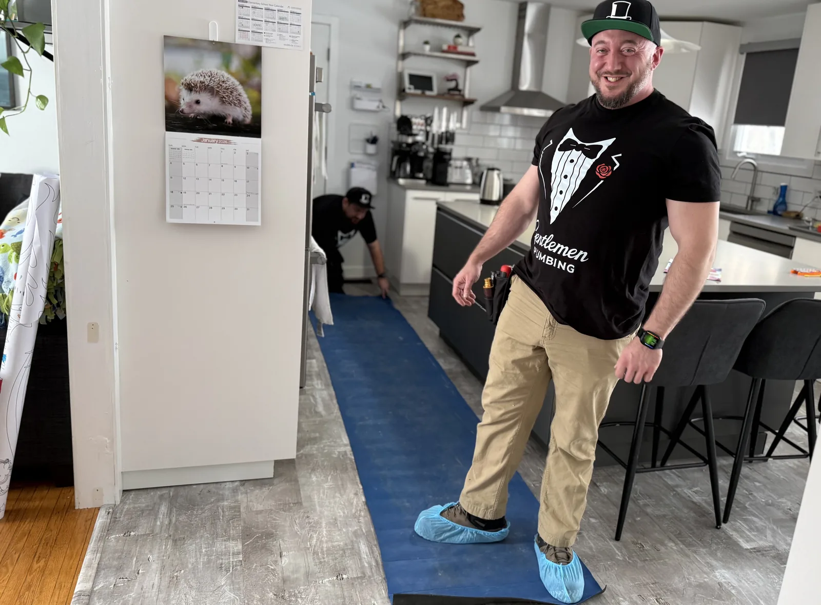 Gentlemen Plumbing technician standing on floor protection in a kitchen.