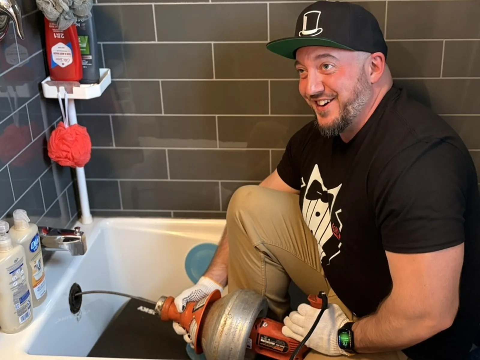 Gentlemen Plumbing technician using a drain snake machine in a bathtub for drain cleaning.